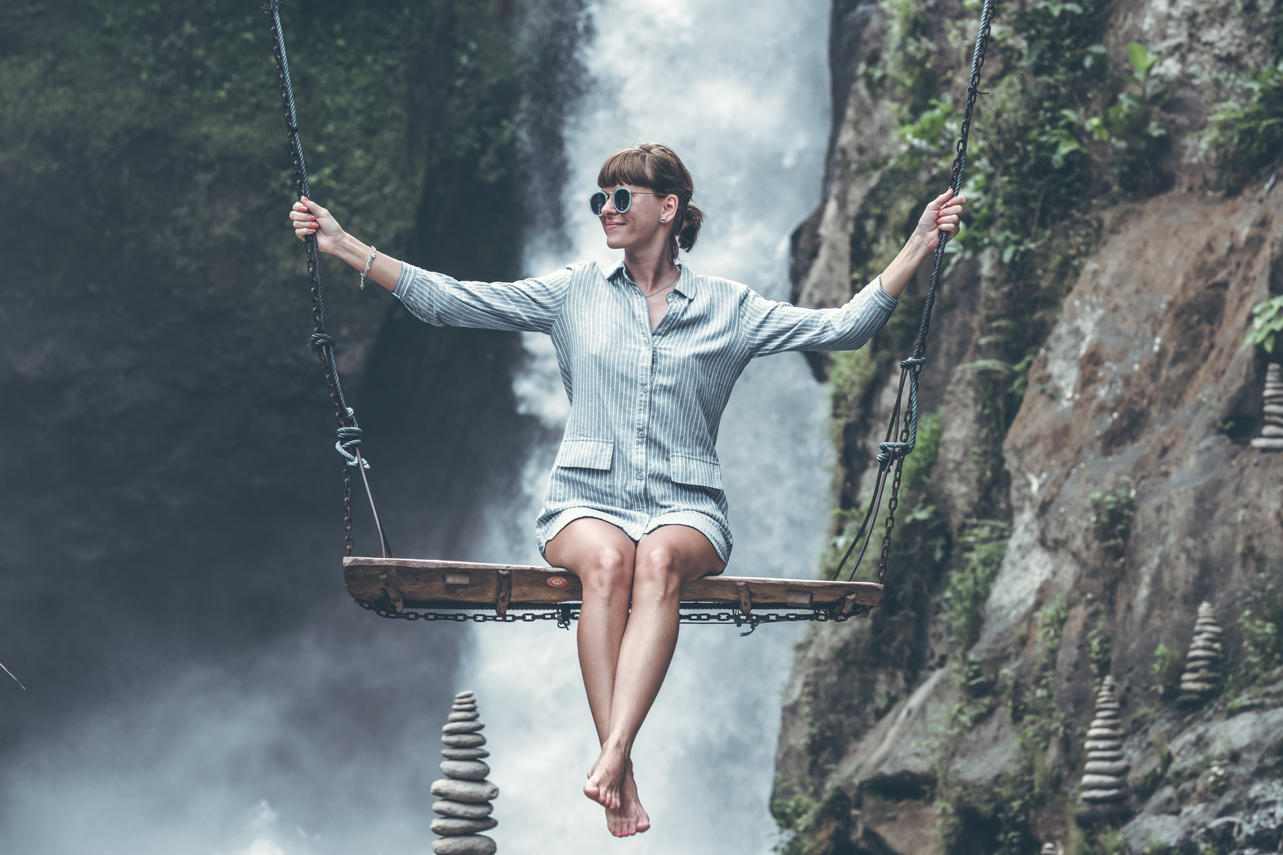 Photo of Woman Riding Swing in Front of Waterfalls